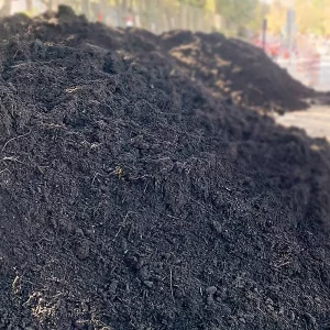 Montón de compost oscuro y húmedo, con textura rica en materia orgánica, utilizado para fertilizar suelos en huertos y jardines.
