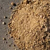 Primer plano de maicillo amarillo con textura fina y compactada, extendido en un camino peatonal rodeado de áreas verdes.